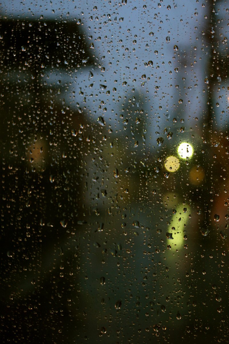 rain drops on a window as cars pass by