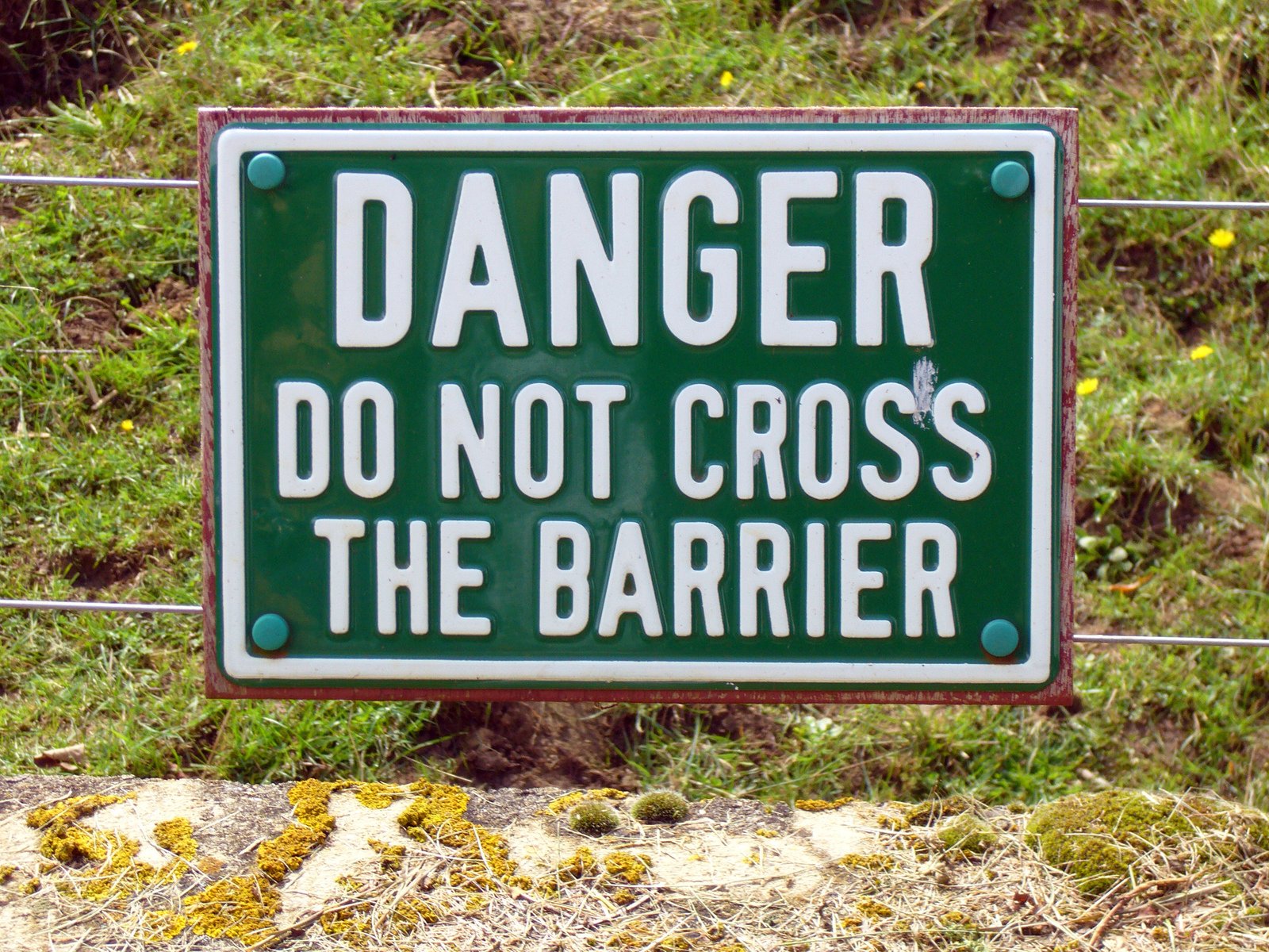 a green sign saying danger do not cross the barrier