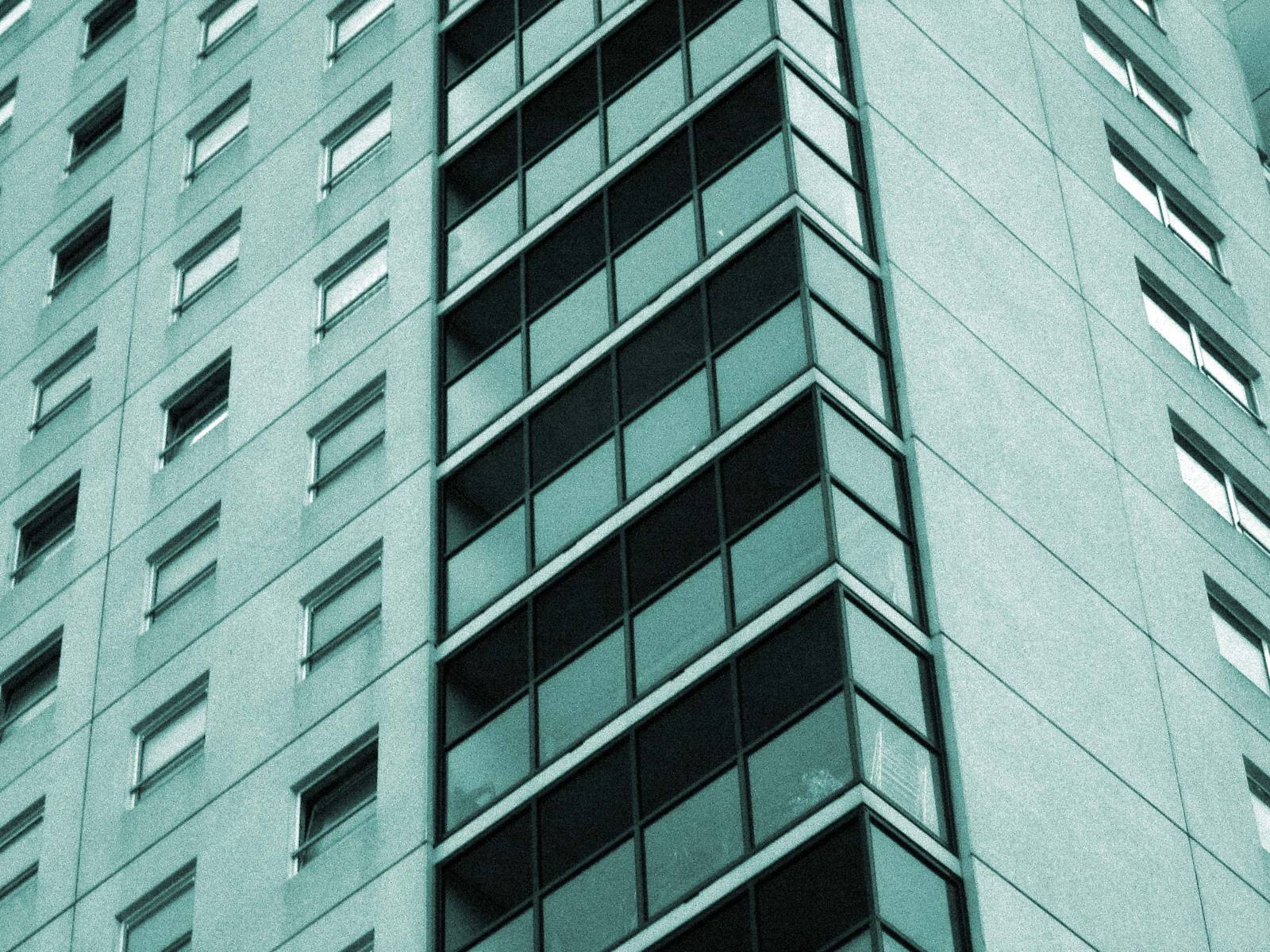 the corner of an tall building with windows