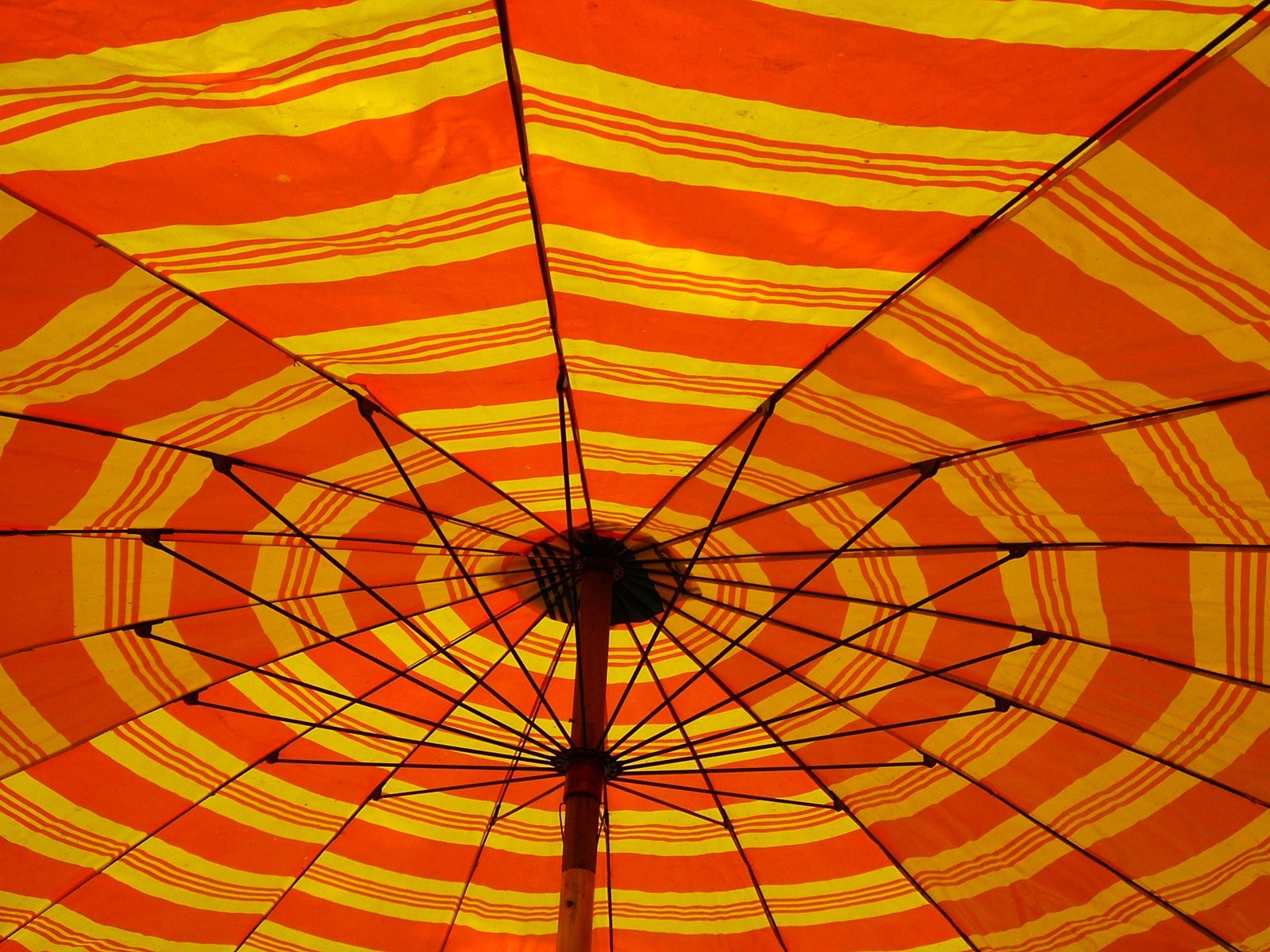 orange striped umbrella is opened above a tall column