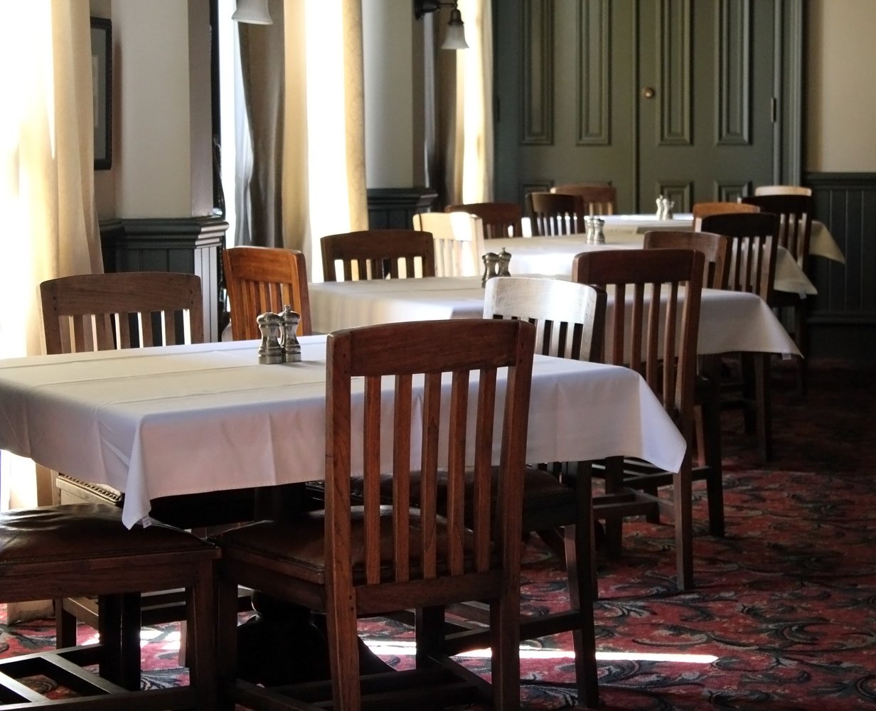 a dinning room with wooden tables and white cloth on the tables