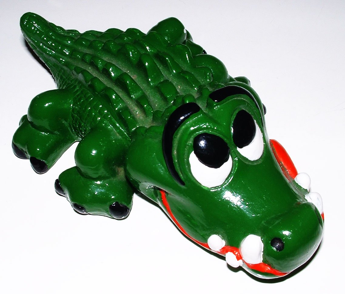 a little green toy crocodile with a red mouth and white teeth