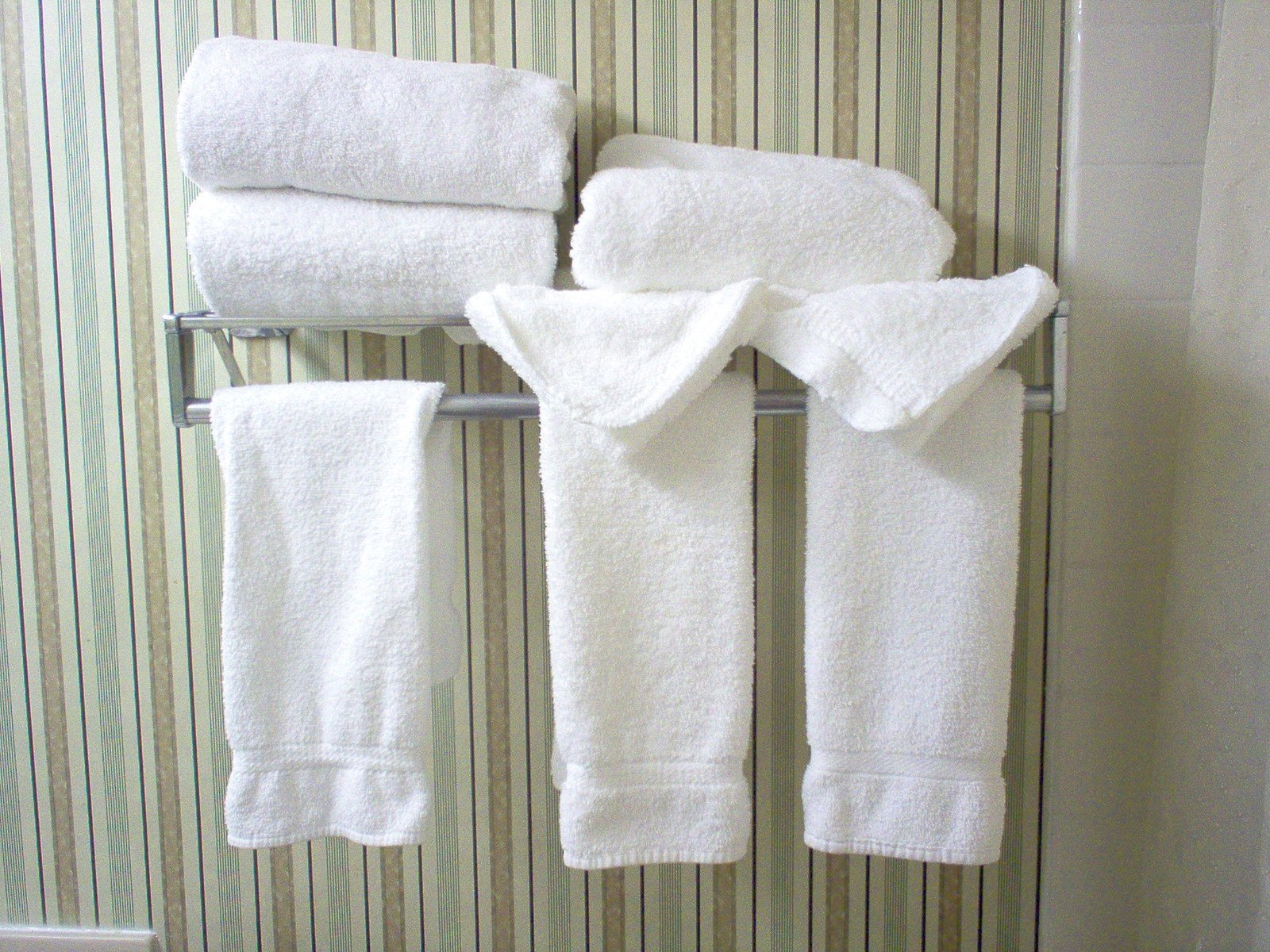 a towel rack holding six white towels
