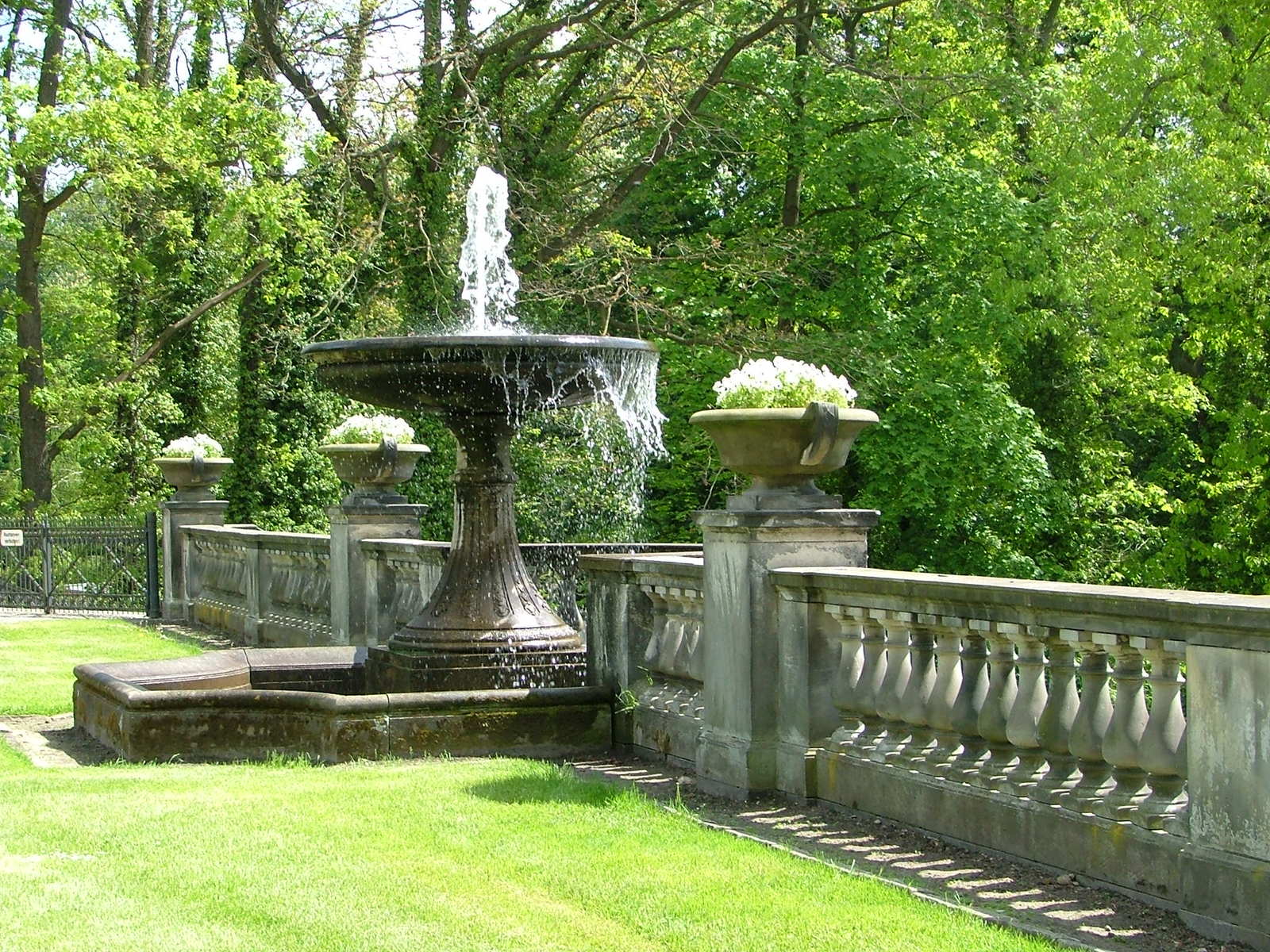 the fountain is in the center of a long garden