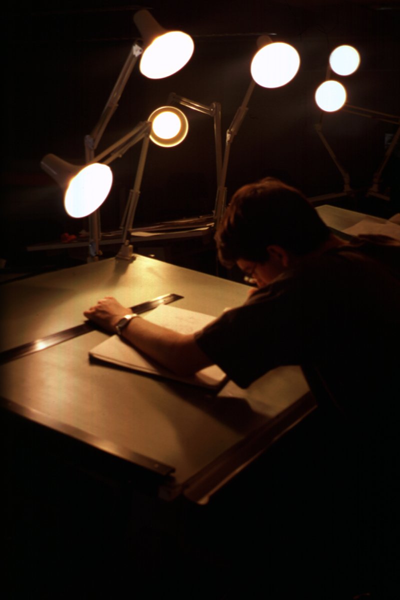 an artist sketching in his studio using a large knife and a big screen light