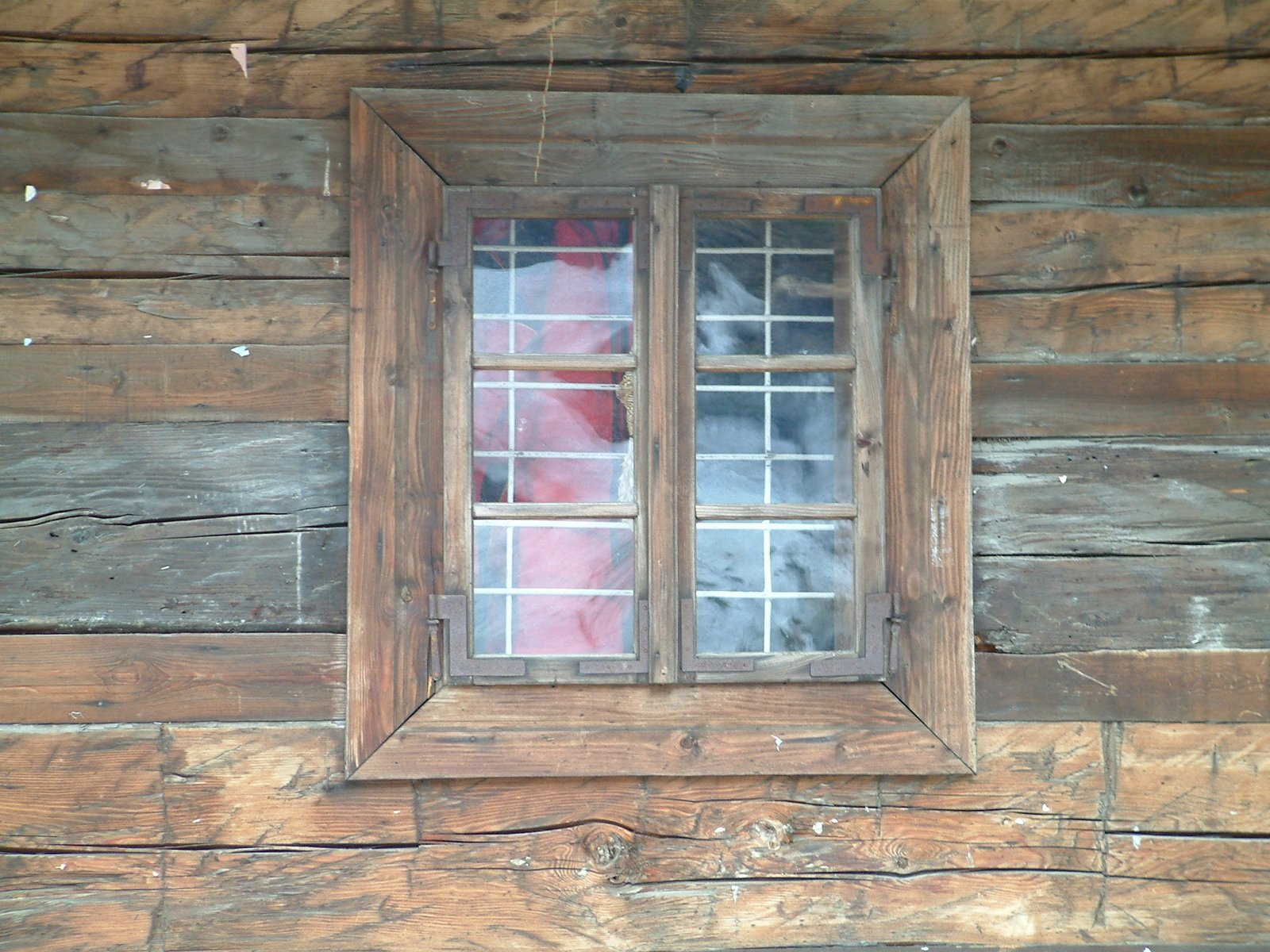 old wooden wall with two window panes that have broken glass