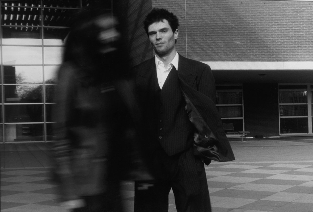 black and white pograph of man in suit near building