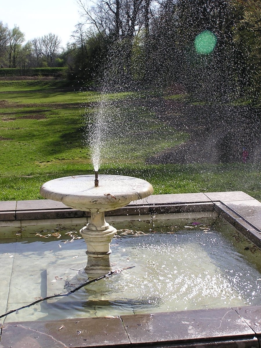 a fountain on top of a park has jets coming out