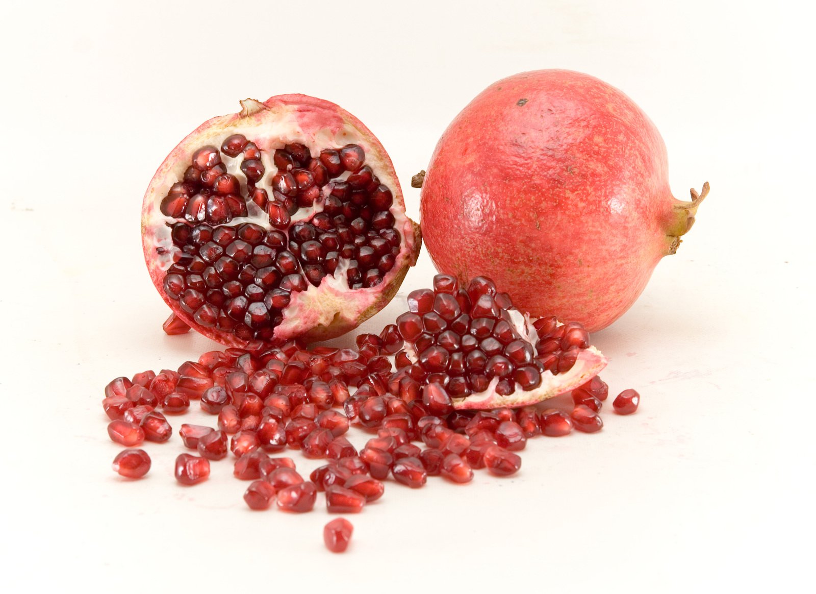 pomegranate and seeds spread across a white surface