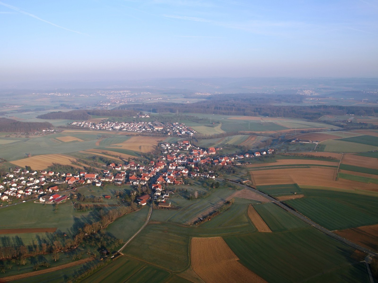 an aerial view of a town and village near many fields
