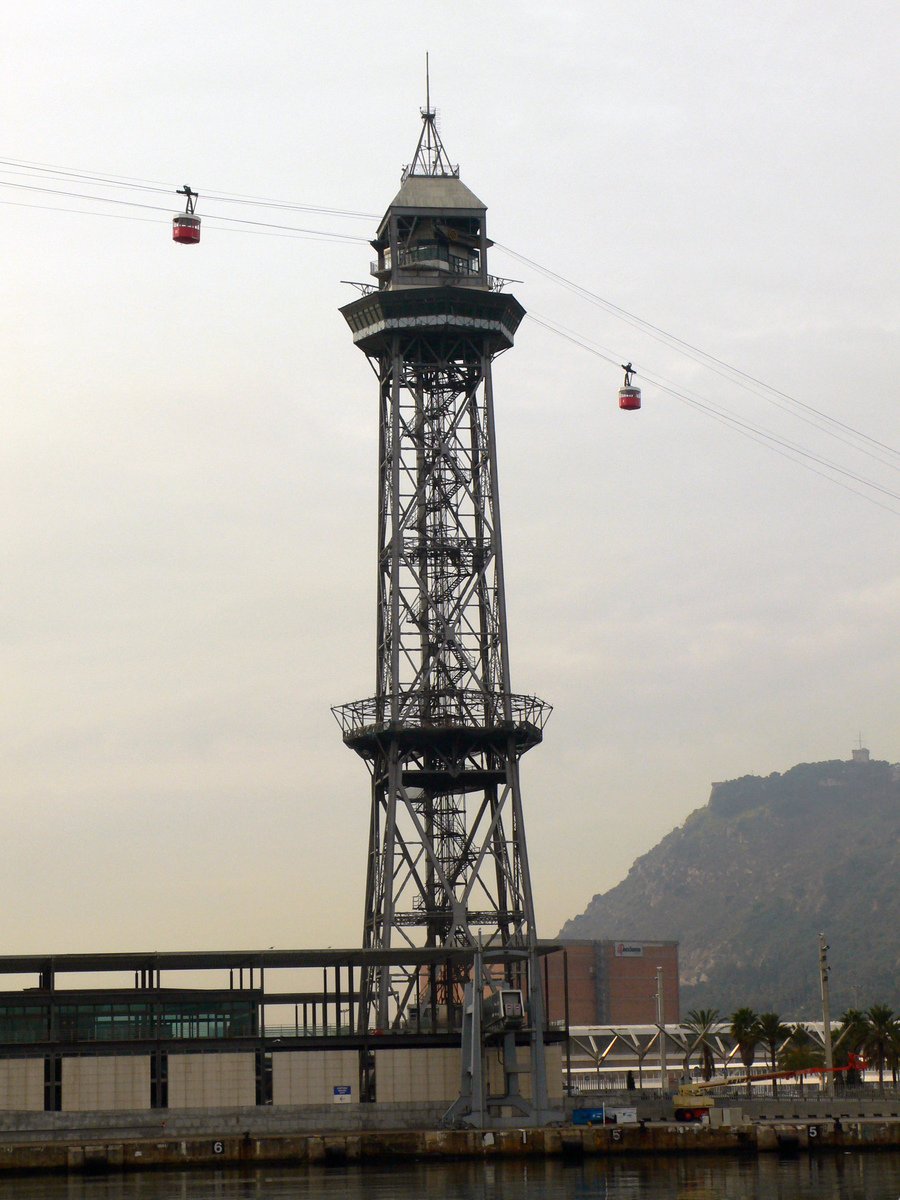 an observation tower near water and buildings with mountains in the background