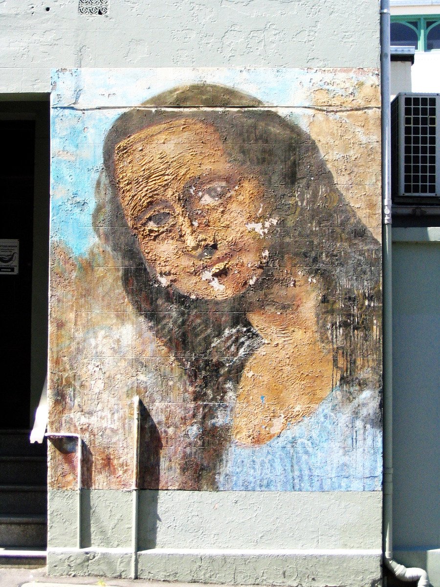 the painted mural of a woman's face and arms on a wall