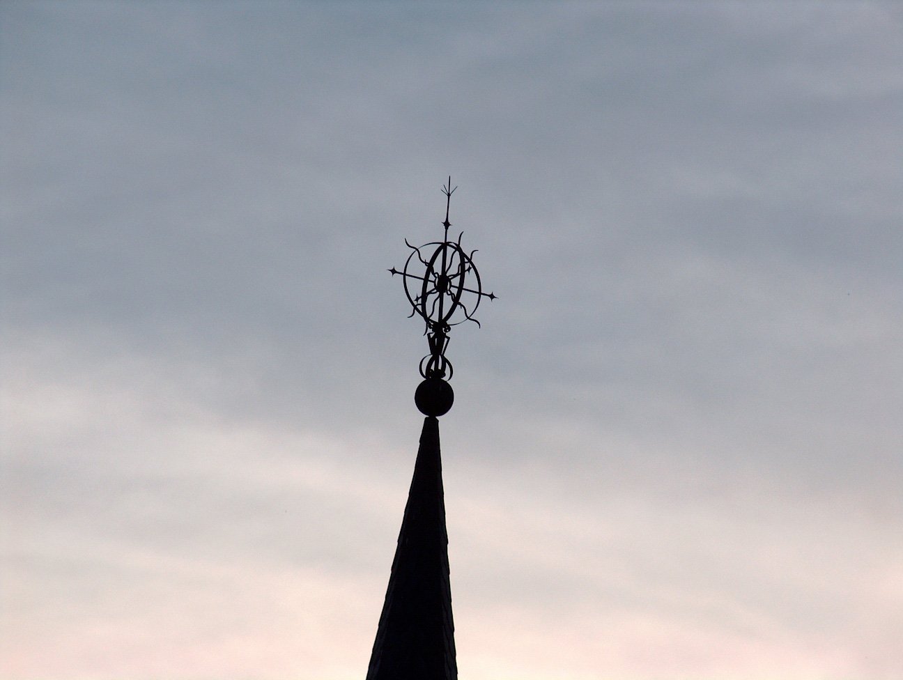 a church steeple silhouetted against a partly cloudy sky