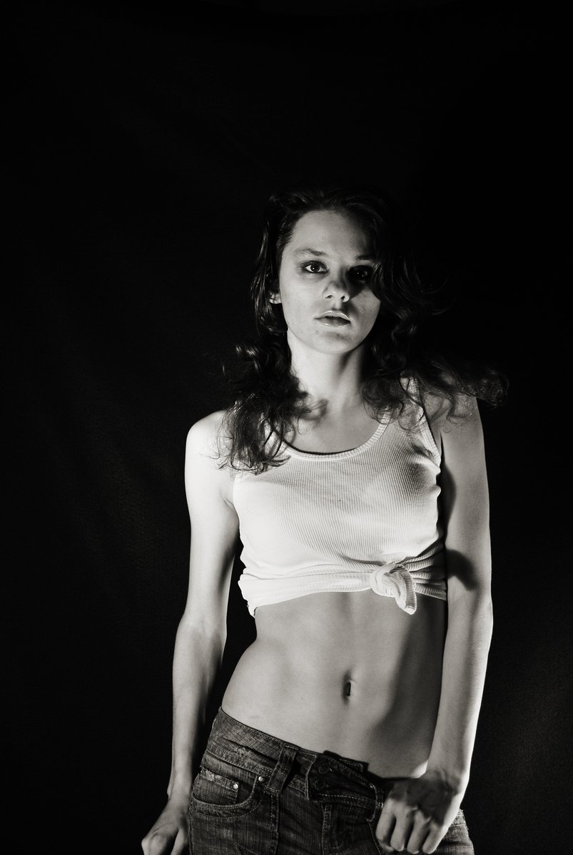 woman in jeans and shirt posing with black background