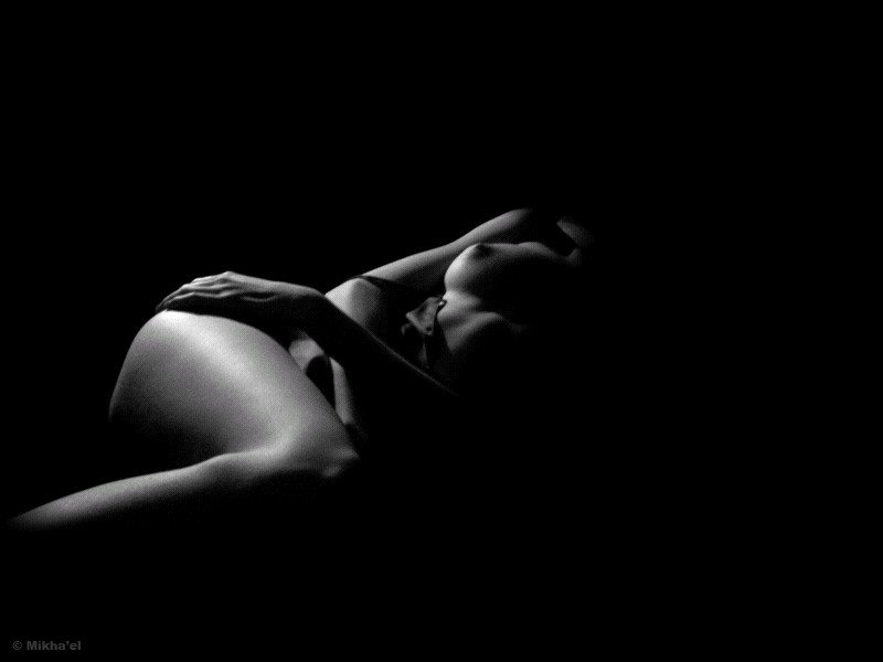 a woman laying in the shadows of her black underwear