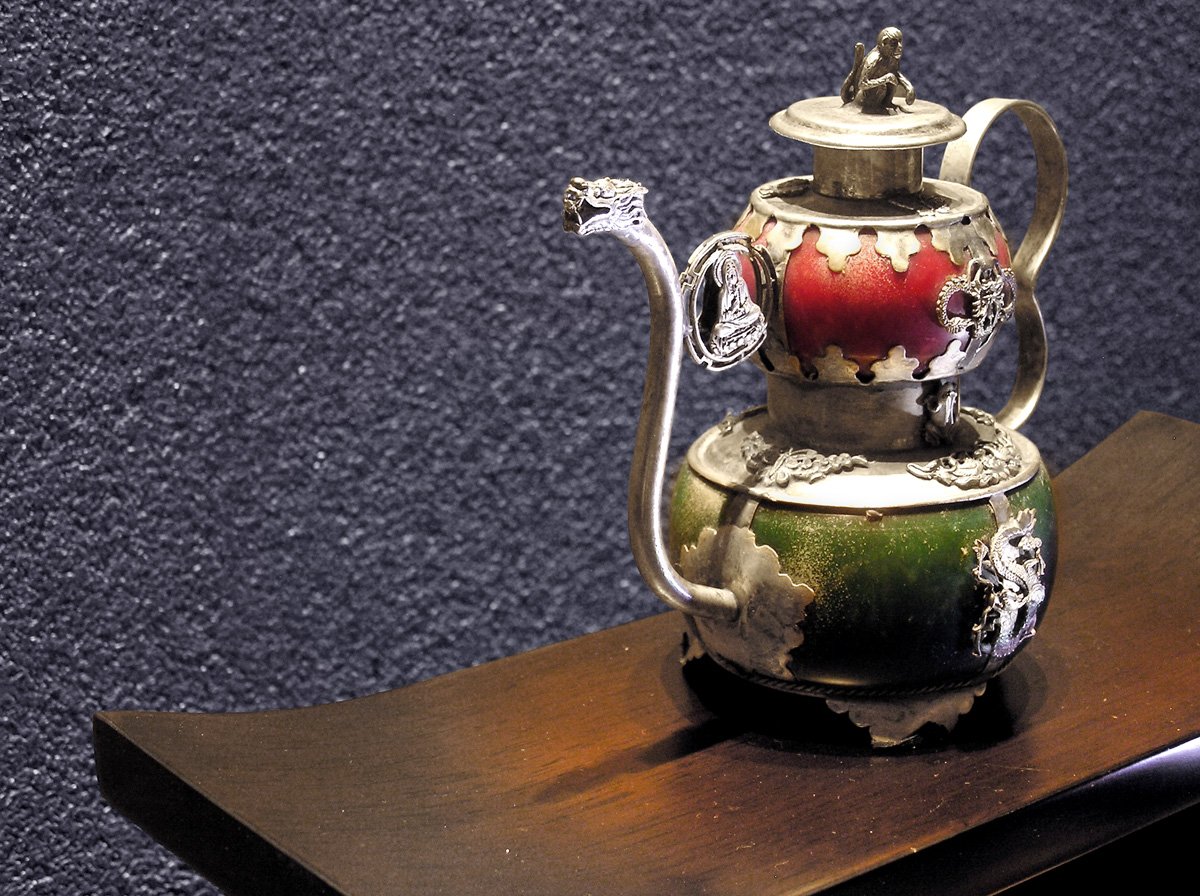 a teapot with a red heart is sitting on a piece of wood