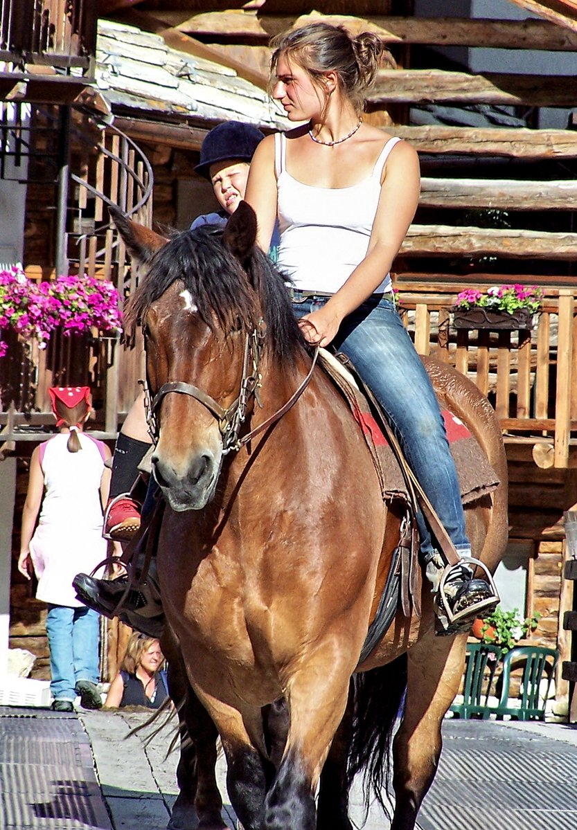 a beautiful young woman sitting on the back of a brown horse