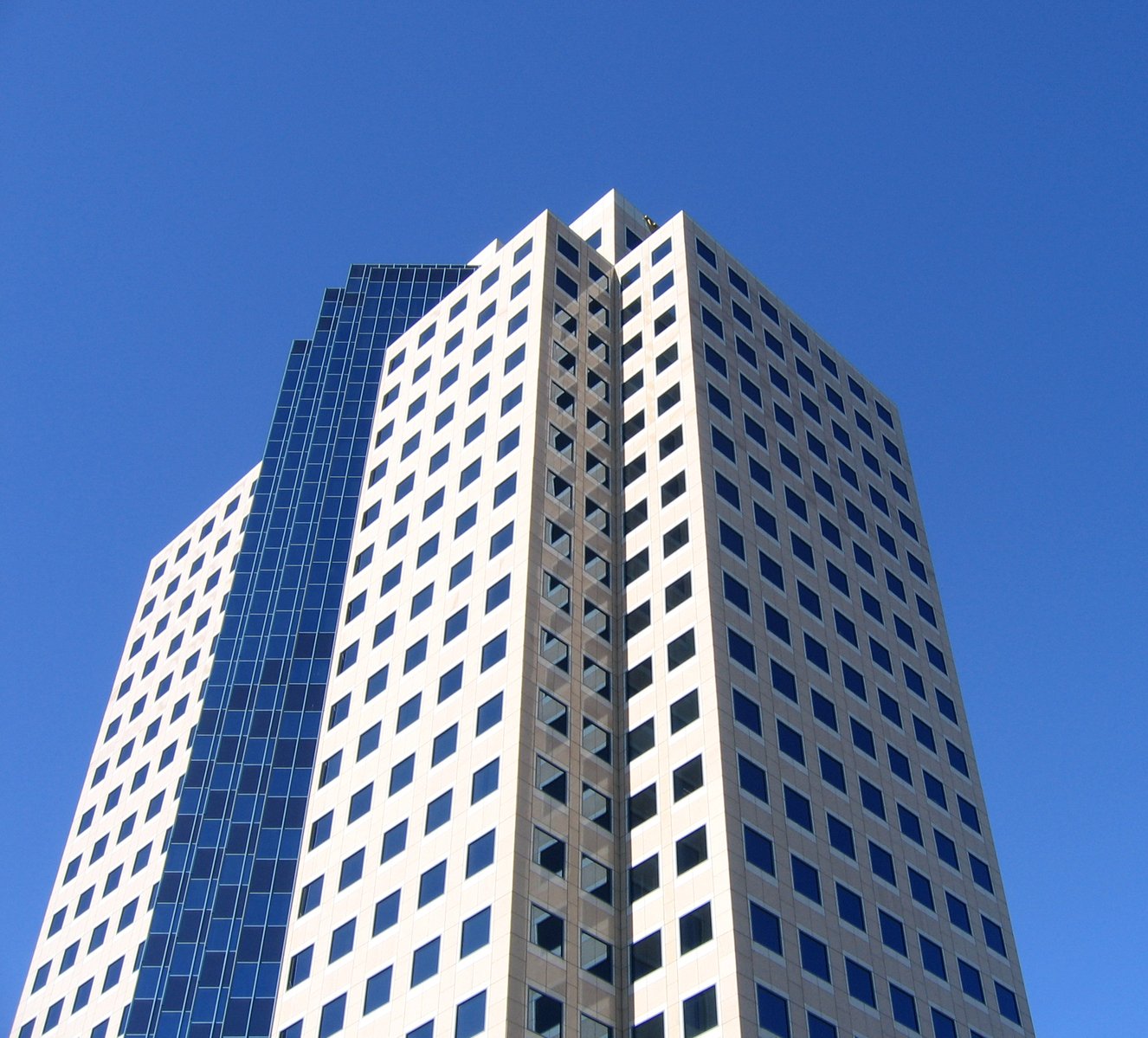 a tall white building sitting below a blue sky