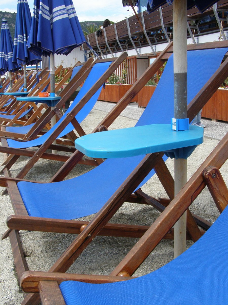 a row of deck chairs with blue umbrellas