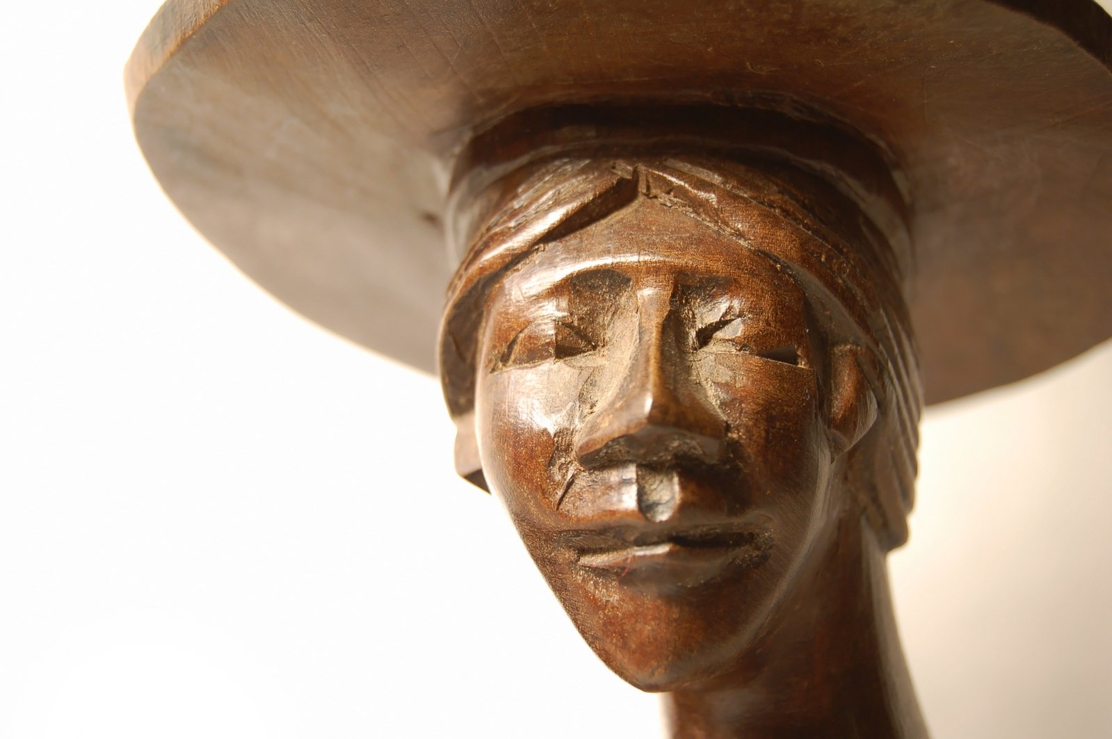 a wooden sculpture wearing a hat with its head sticking out