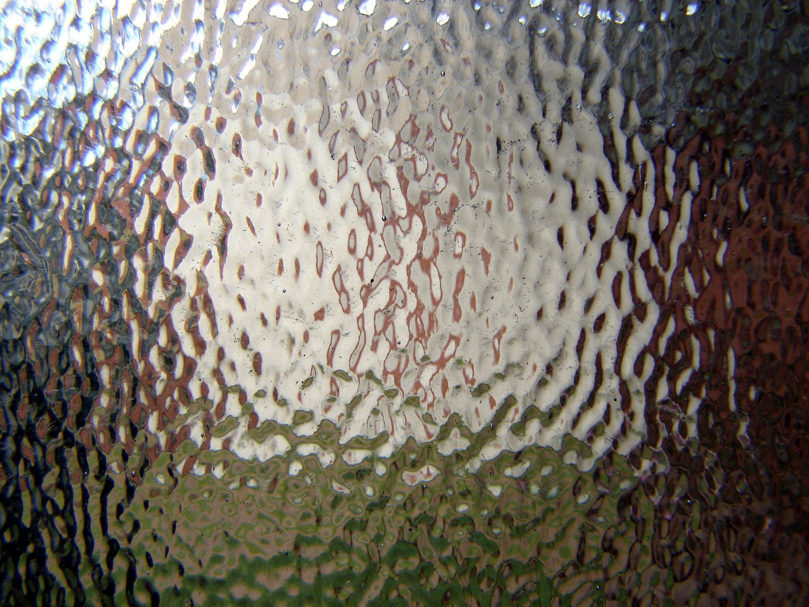 a window with water drops on it and red brick buildings in the distance