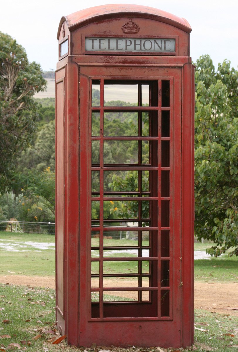a old phone booth sits in the grass