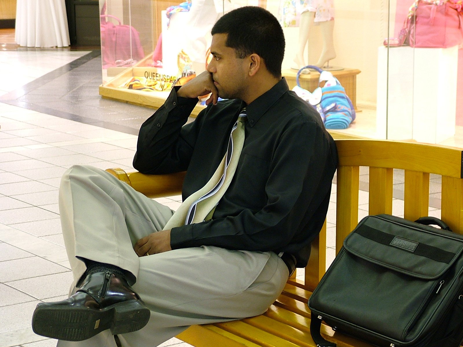 a man sitting on a wooden bench talking on a cell phone