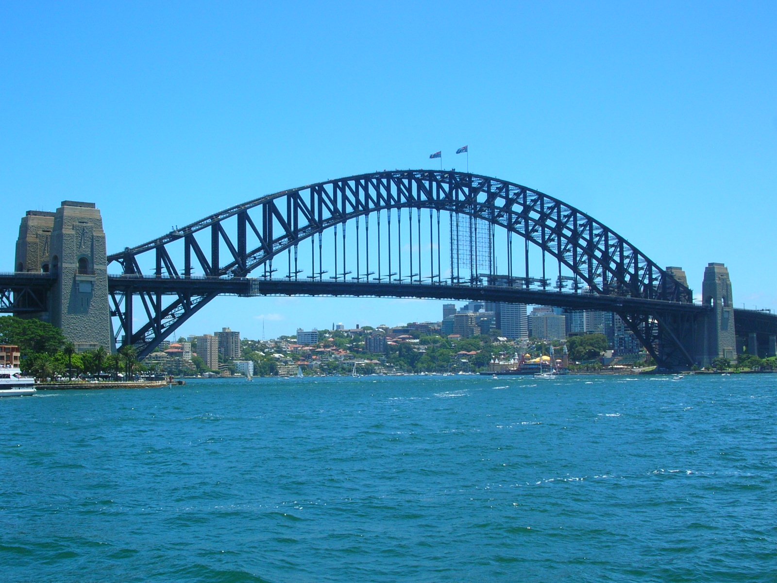 a large bridge spans over the water by a city