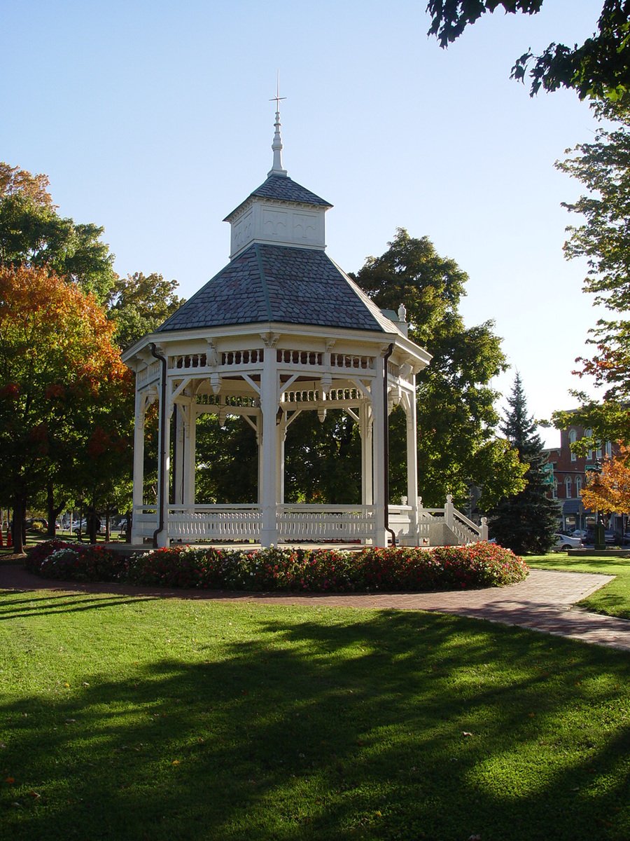 the small white gazebo sits among trees and bushes