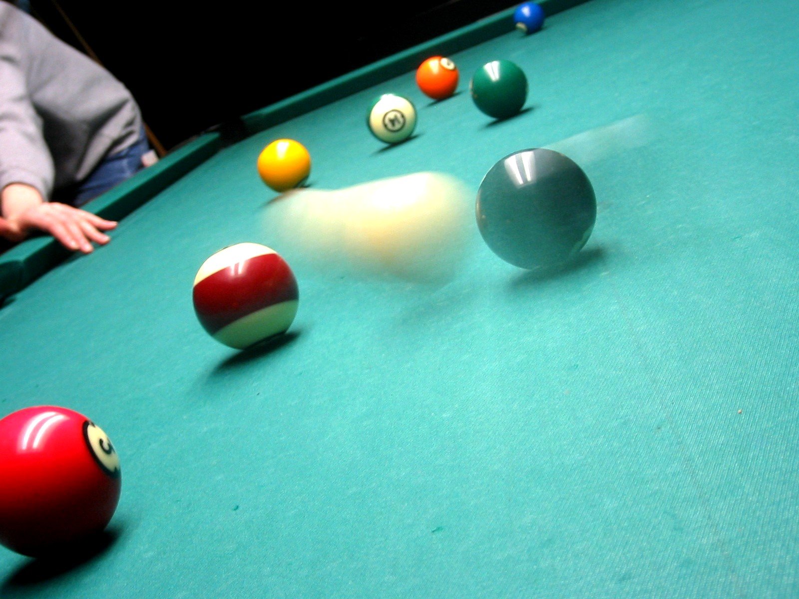 some balls and cues on the green table