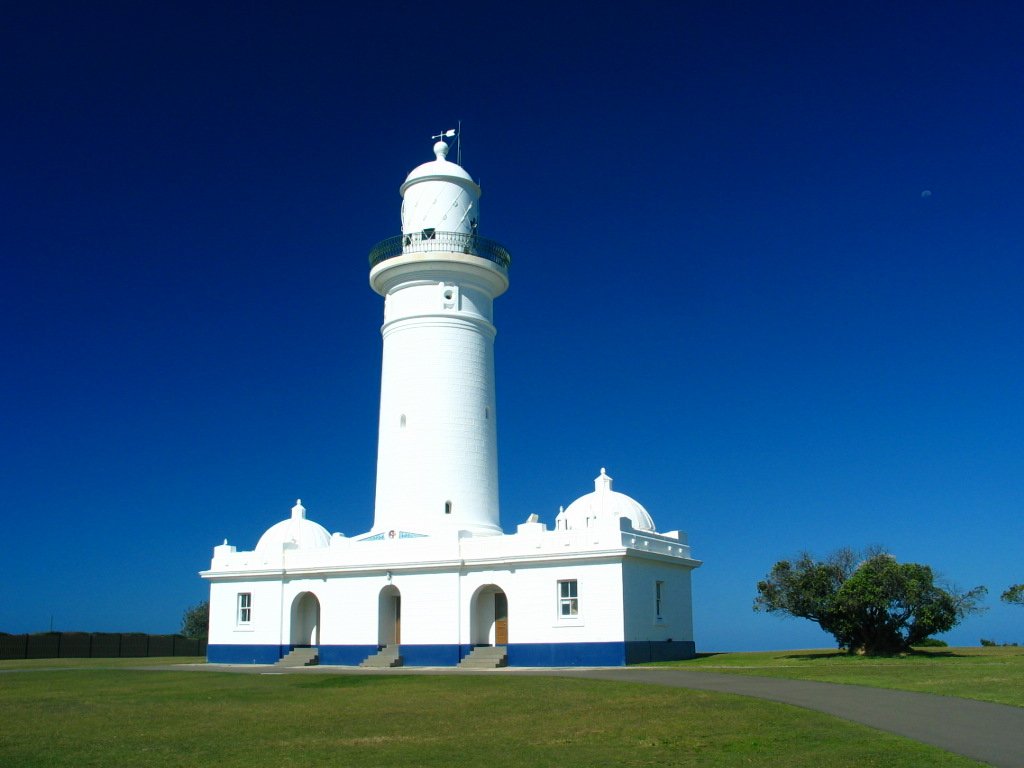 a tall white lighthouse standing on top of a lush green field