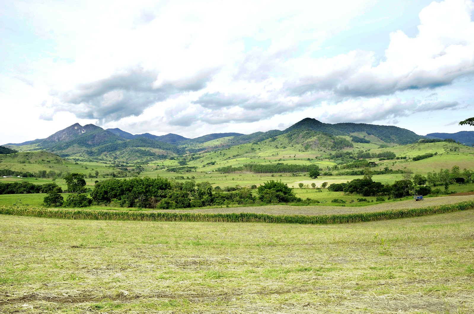 an open field surrounded by mountains under a blue sky