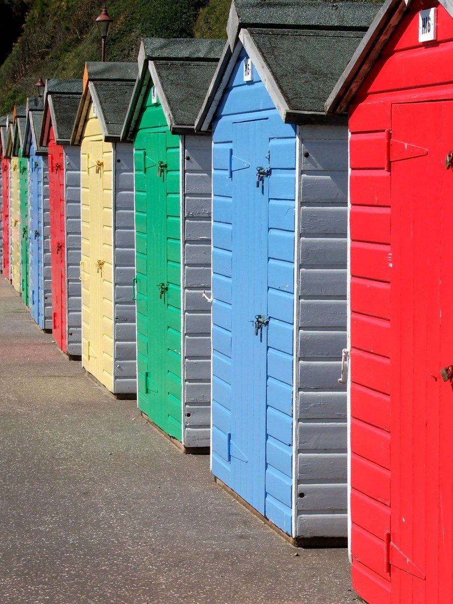 many different colors of beach huts lined up next to each other