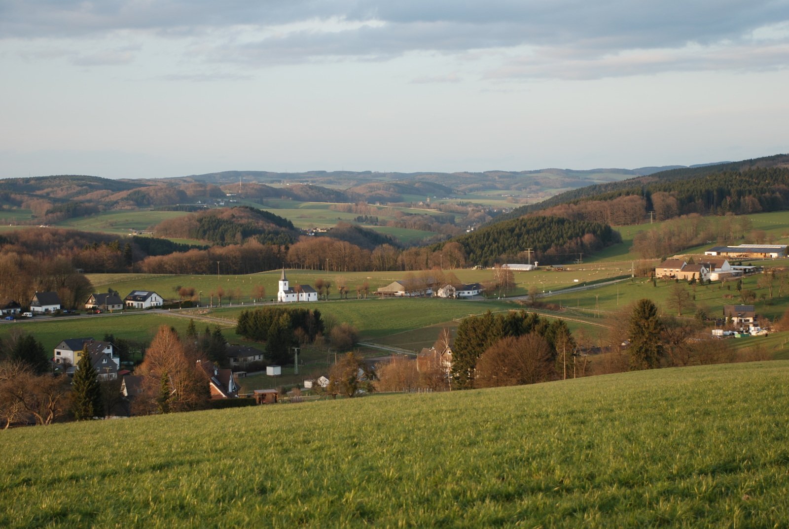 looking down on some countryside with fields, houses and churches