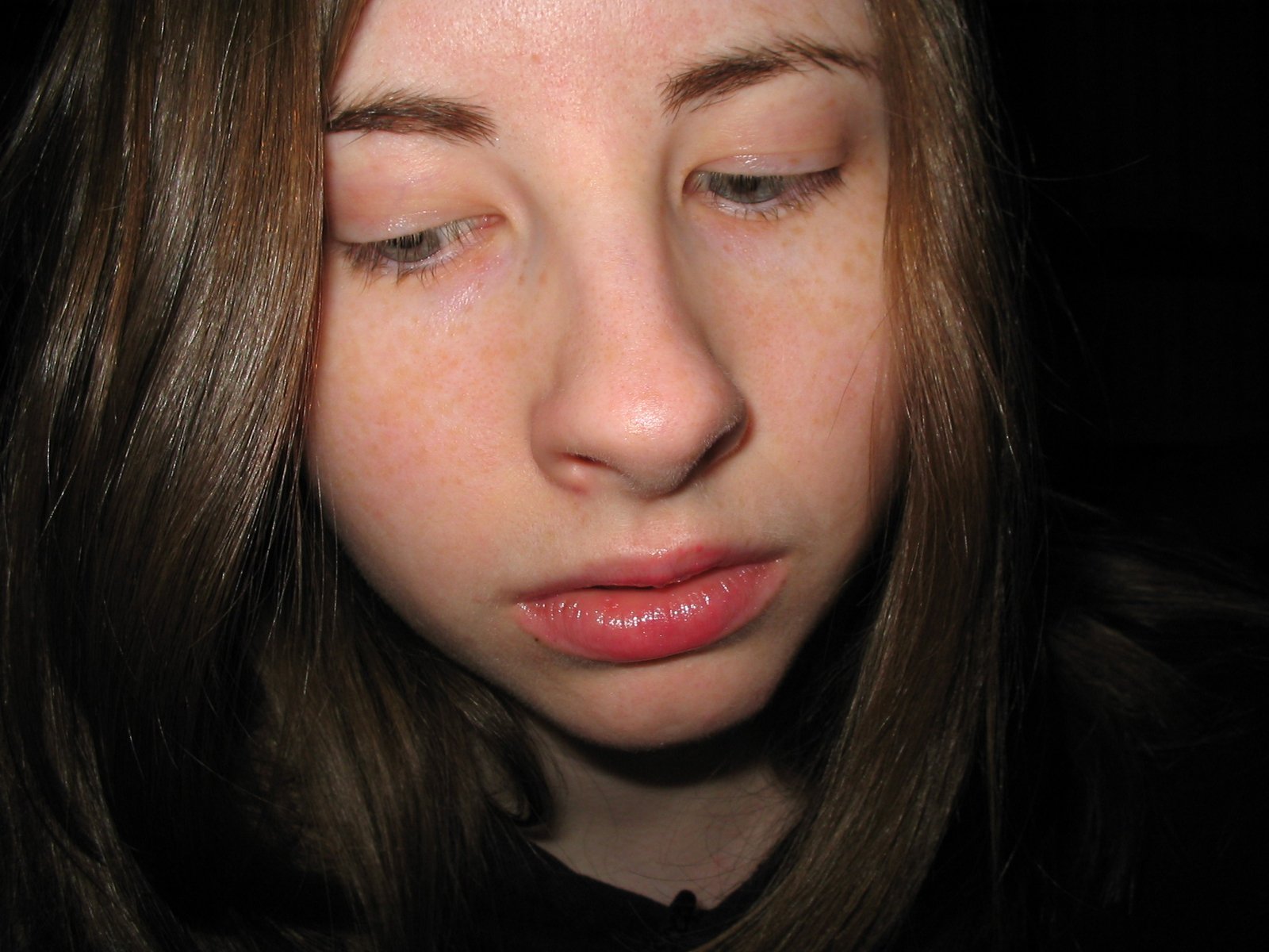 a girl with very brown hair holds her nose and looks into the distance