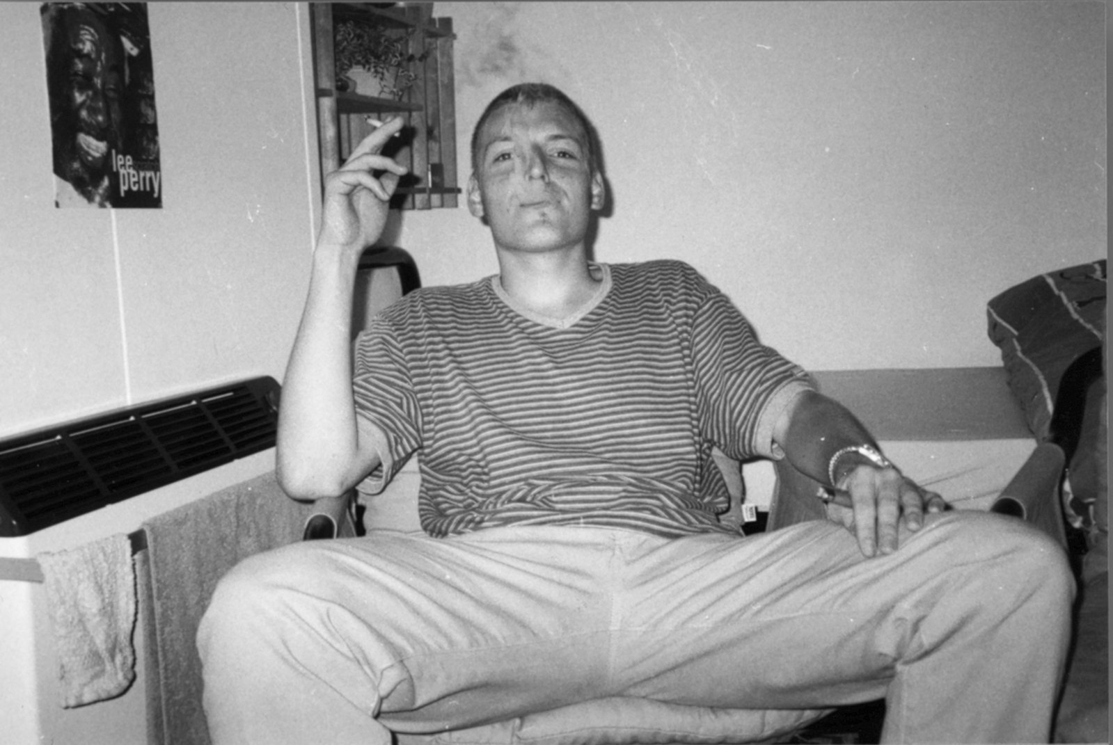 a man smoking a cigarette sitting on a couch in front of a wall