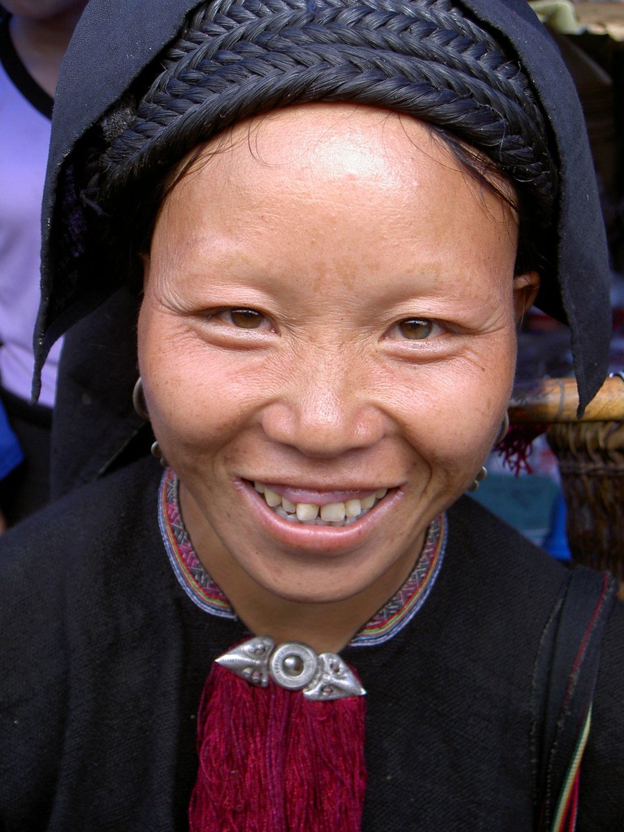 a smiling woman wears a traditional black hat