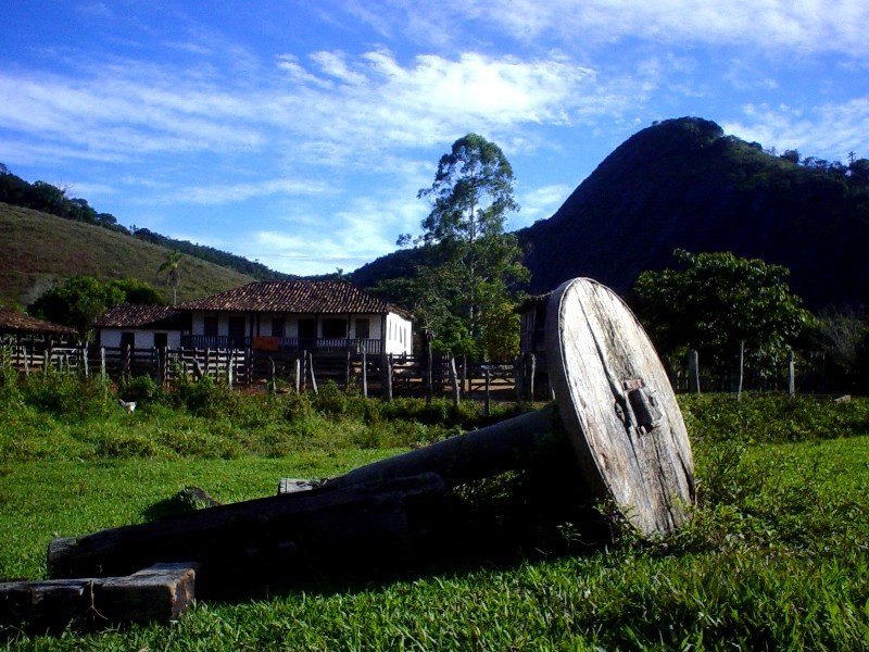 a large wooden wheel in the middle of a lush green field