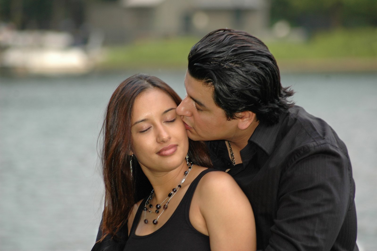 a man and woman kissing in front of the water