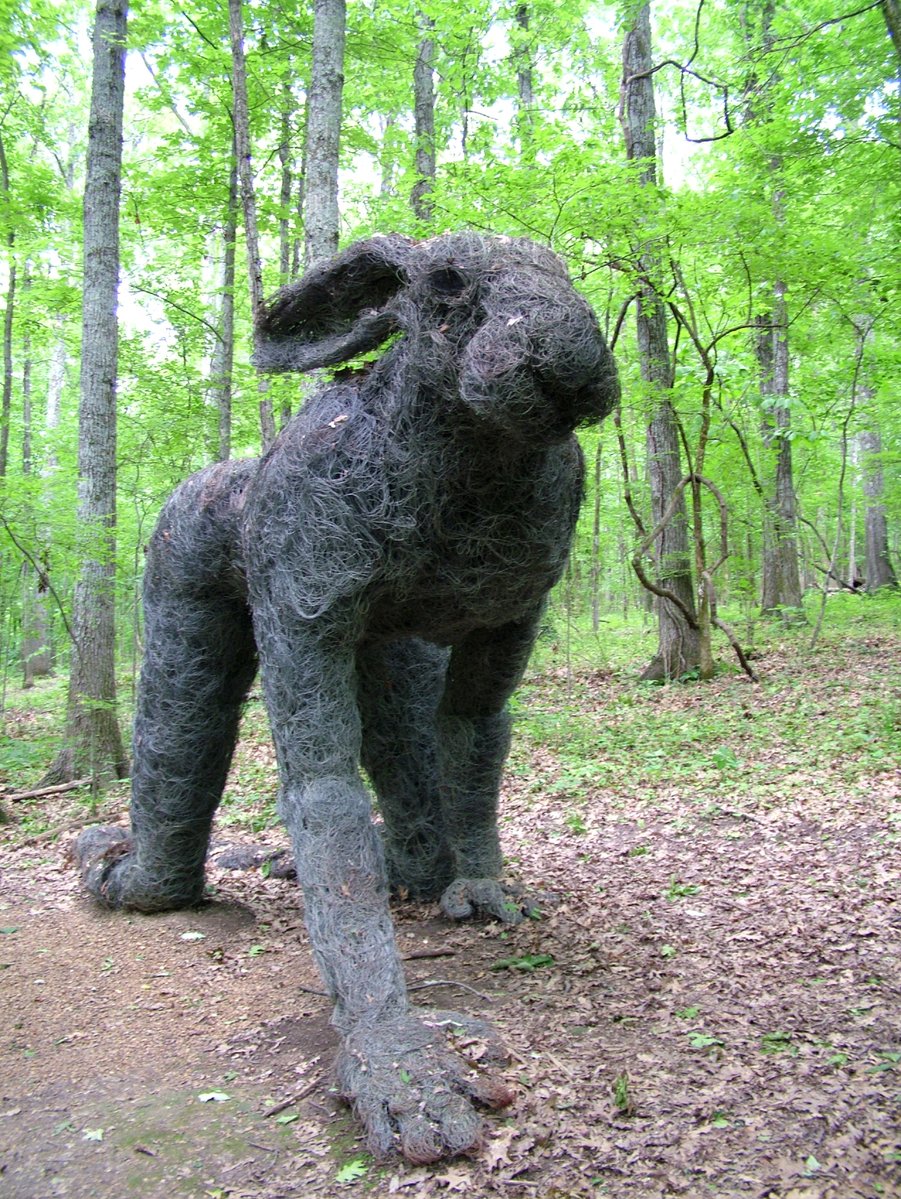 a sculpture of a dog is in the middle of the woods