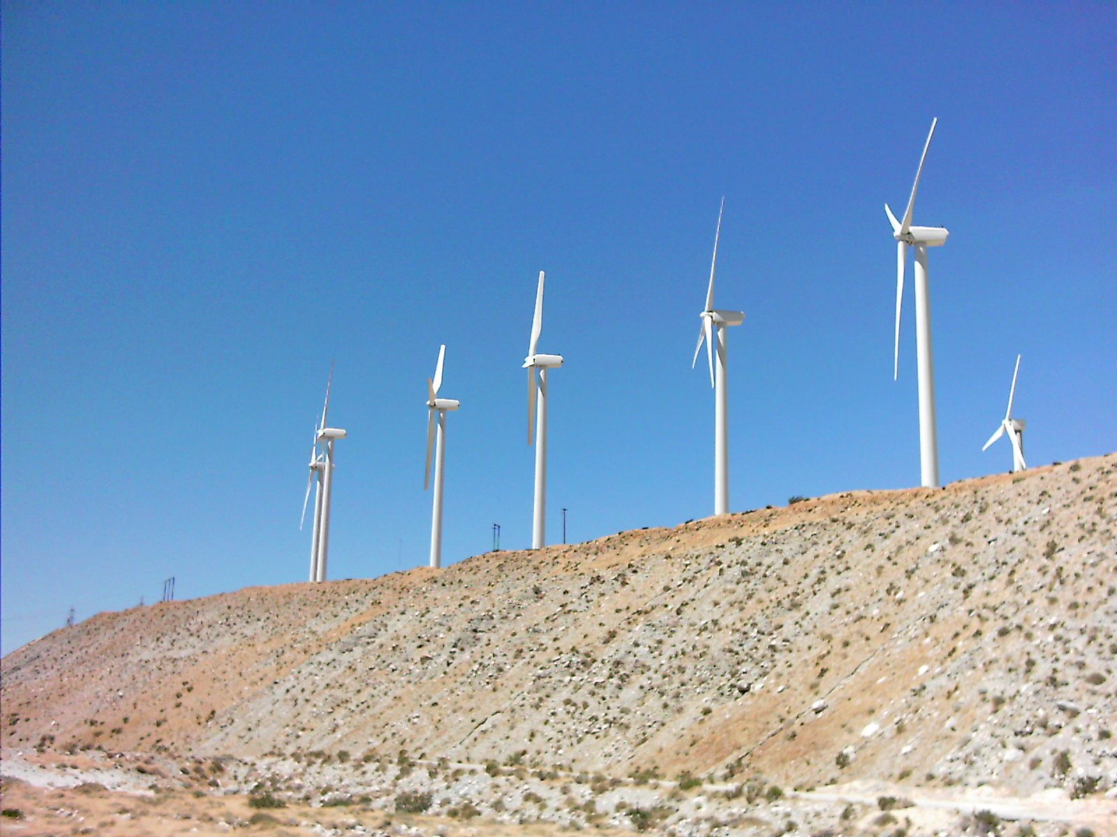 wind turbines are standing near the side of a mountain