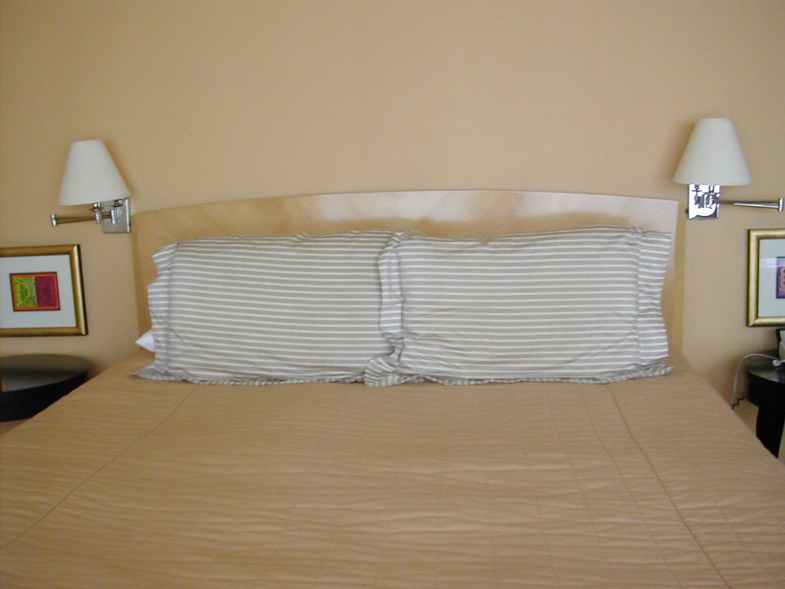 a bed has a beige bedspread with white pillows