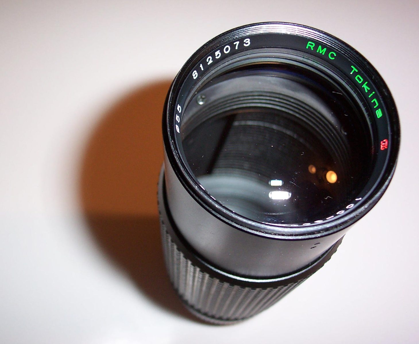 a camera lens is shown with an empty cup nearby