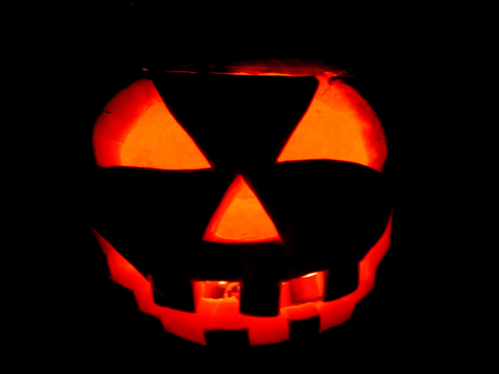 a glowing halloween pumpkin face with a cross at the top
