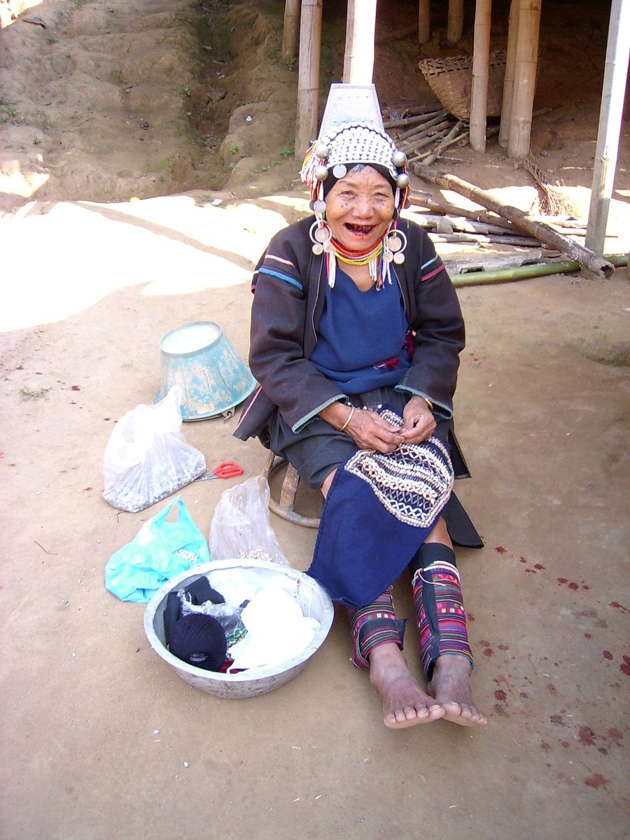 an old woman wearing a hat sitting on the ground