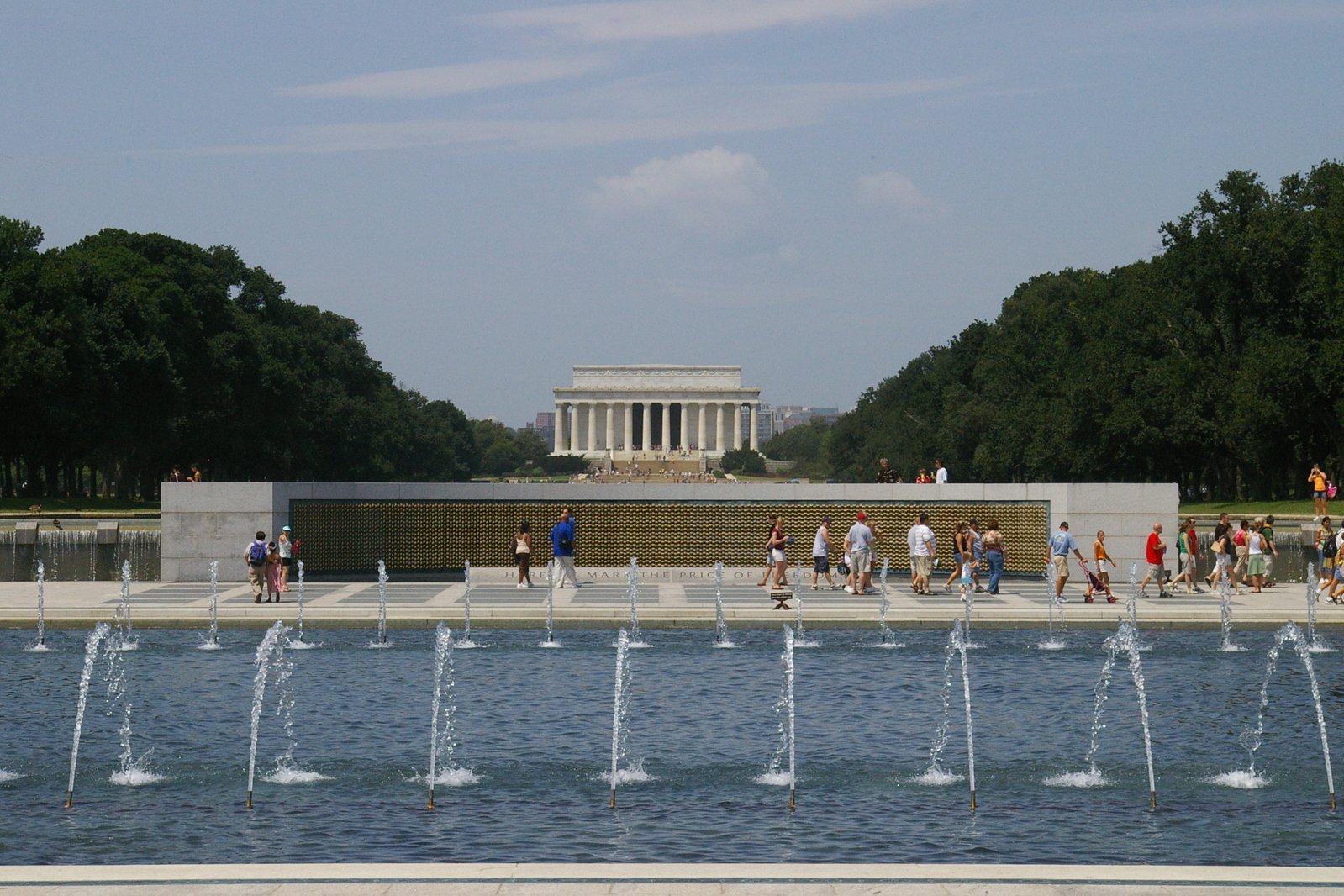 a large memorial features three fountains and a clock tower in the background