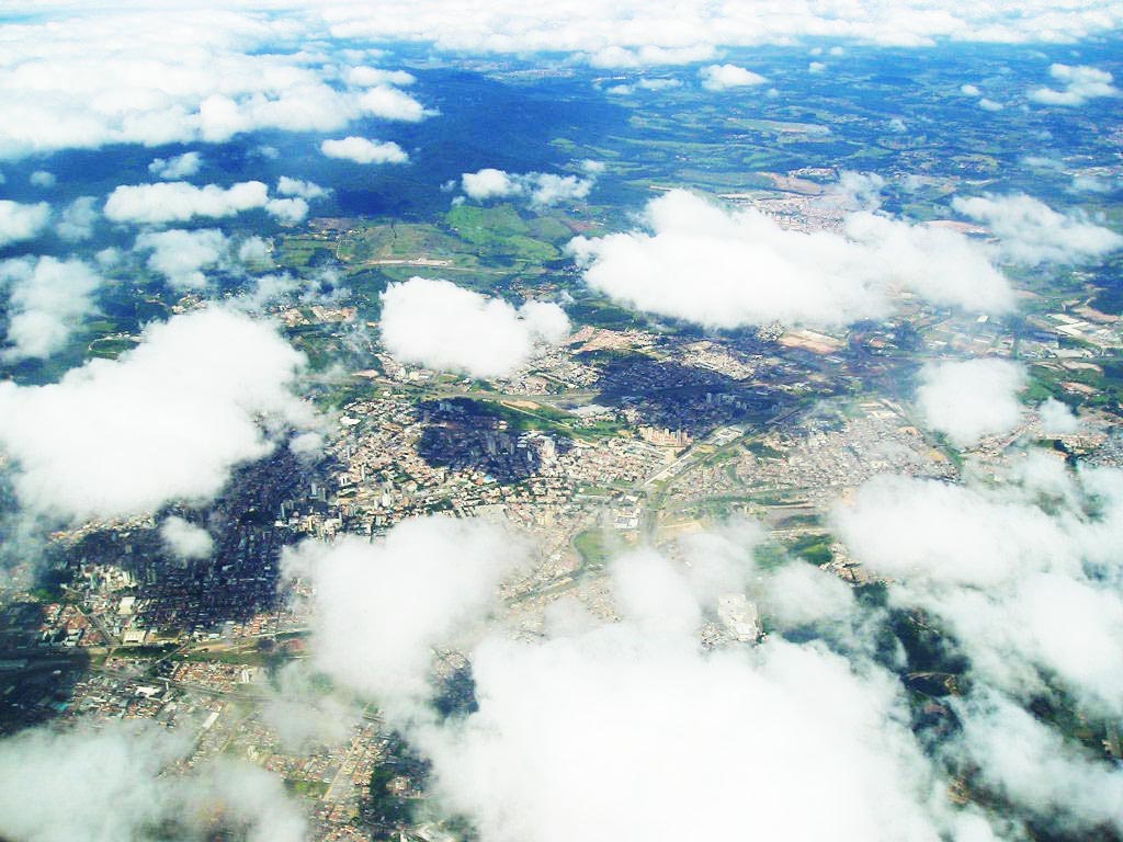 an overhead view shows clouds, buildings, and trees