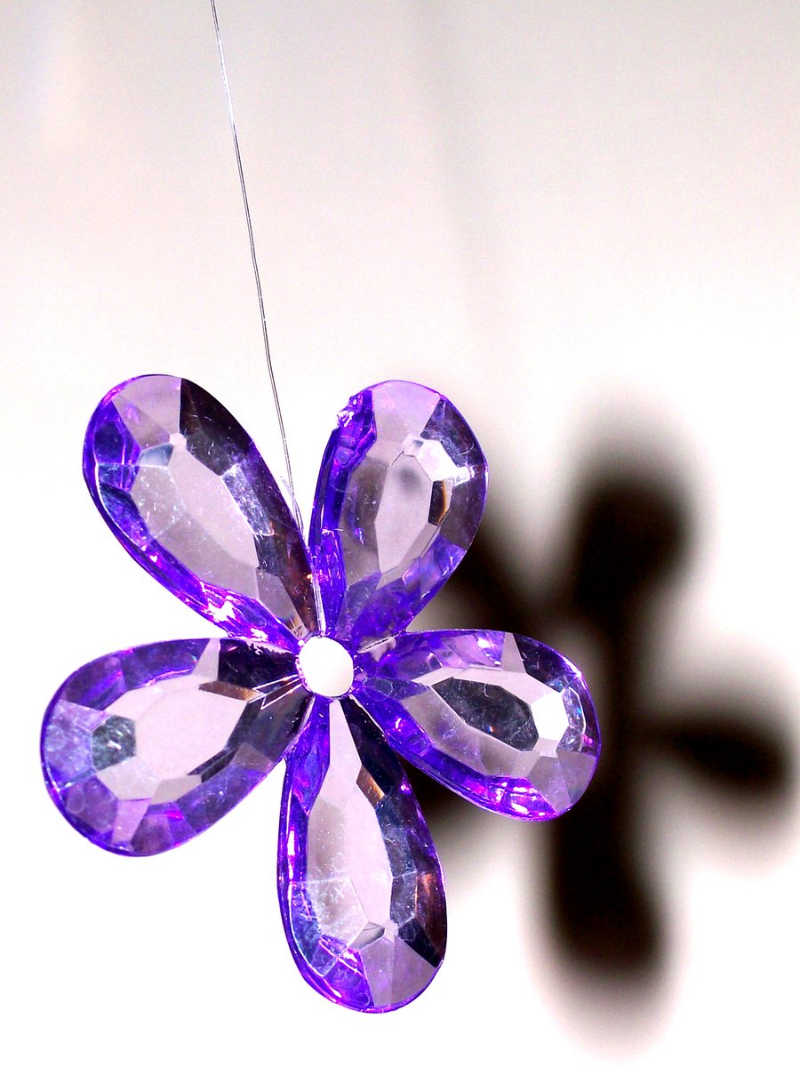 a hanging purple glass flower hangs from a cord