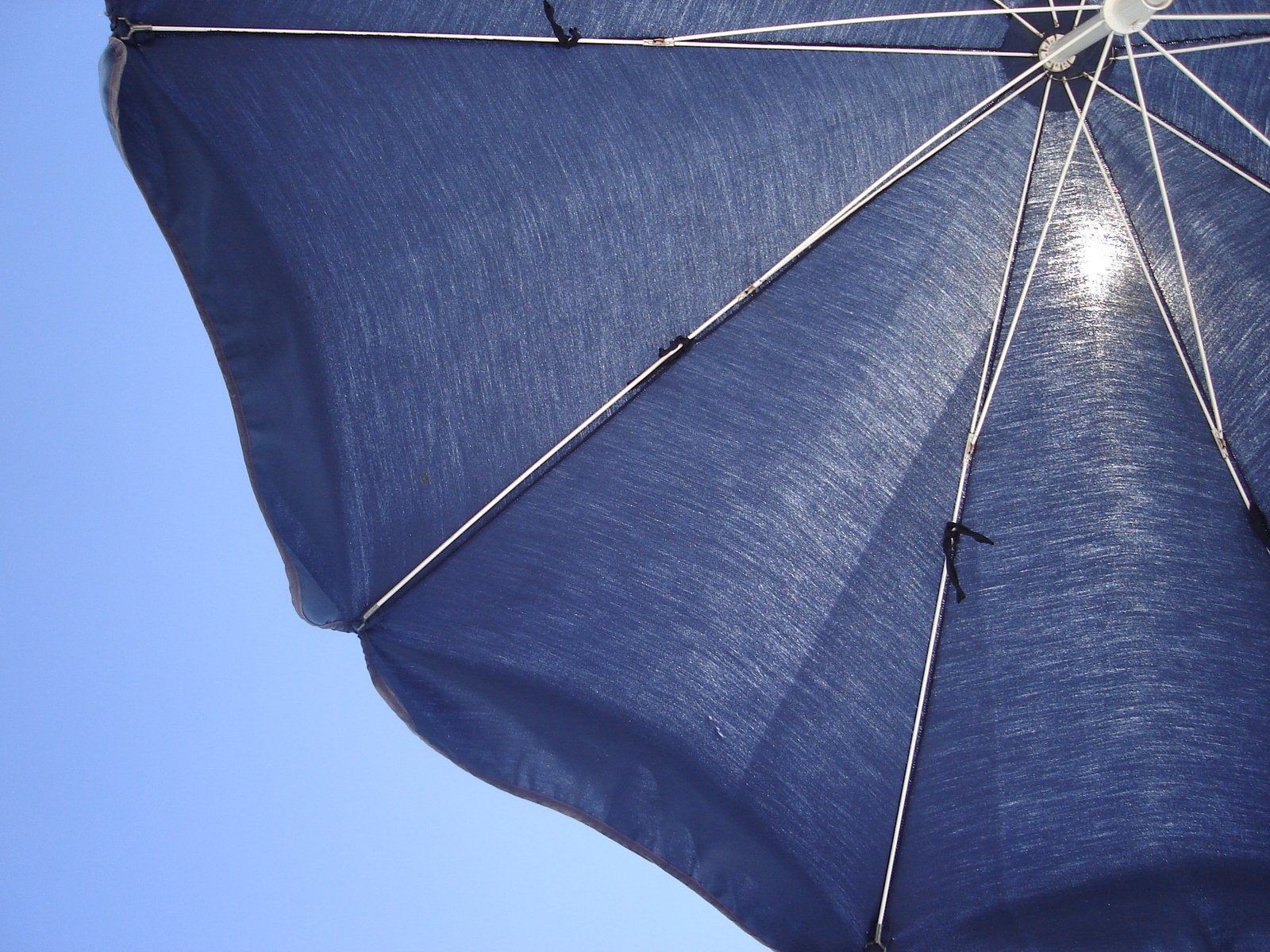 a blue umbrella is opened against a bright blue sky