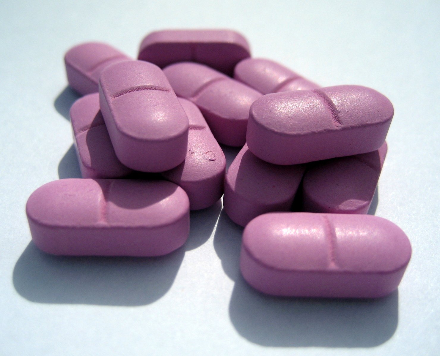 a pile of pink pill pills sitting on a blue table